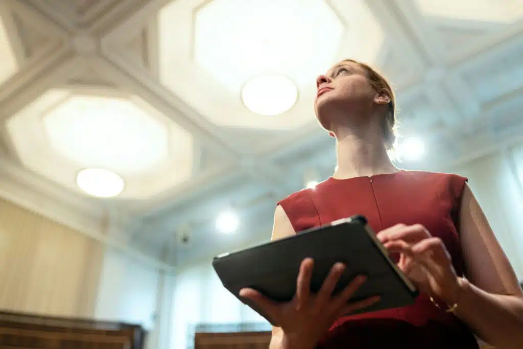 Female engineer in an elegant auditorium looking focused while using a digital tablet for testing technology.