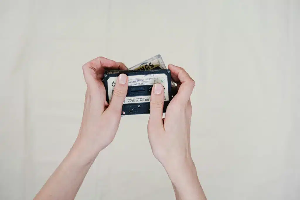 Close-up of hands holding vintage cassette tapes on a plain background, emphasizing retro music vibes.