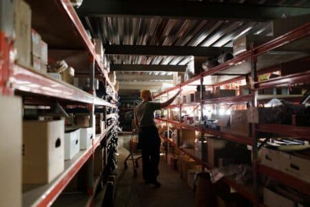 A warehouse worker arranging inventory on metal shelves in a storage facility
