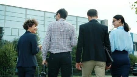 Group of business professionals walking outdoors near a modern office building.