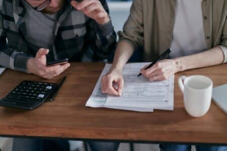 A couple collaboratively managing finances with papers and calculator in hand.